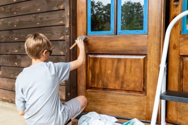 Person working on applying wooden door with protective urethane coating clipart