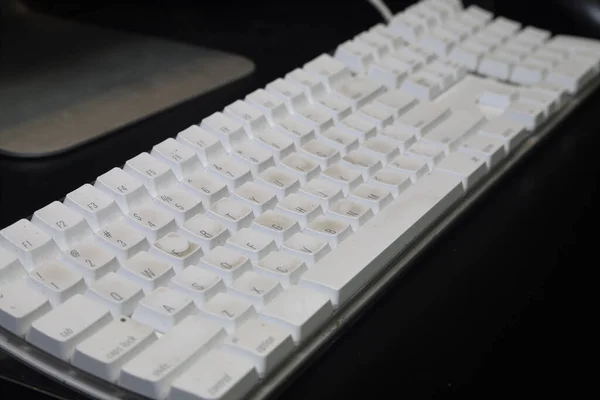 white computer keyboard on black desk
