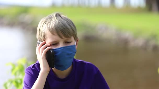 Niño hablando por teléfono celular mientras usa mascarilla facial durante la pandemia — Vídeo de stock