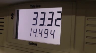 Yakıt pompasında galon ve dolar miktarı artarken, benzin aracı dolduruyor.
