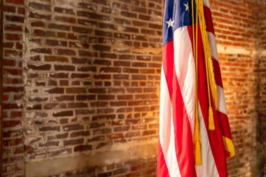 American Flag on Stand, against old brick wall, with copy space. clipart