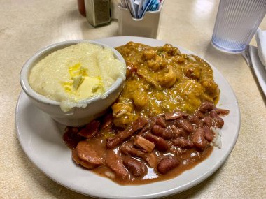 Kerevit Etouffee, Red Beans & Rice ve Grits bir tabakta, geleneksel New Orleans yemekleri.