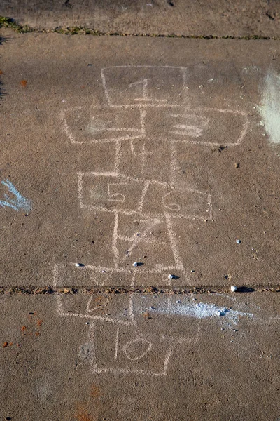 Hopscotch board drawn with sidewalk chalk on gray concrete pavement background