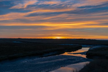 Sankt (St.) Peter Ording, Almanya yakınlarındaki muhteşem renklerle ve dramatik gökyüzüyle Kuzey Denizi 'nde büyüleyici bir gün batımı.