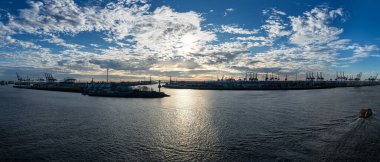 Hamburg Limanı 'nın konteyner terminali ve Elbe Nehri' ndeki Khlbrandbrcke köprüsü ile gün batımında rıhtımın çatısından göz kamaştırıcı panoramik manzarası.