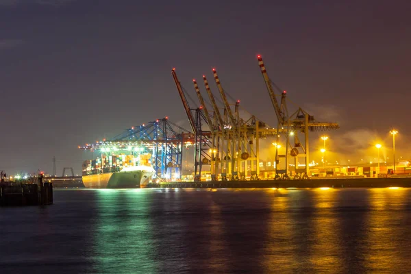 夜间在汉堡的一个灯火通明的货运港口 拥有集装箱码头 起重机和蓝天 — 图库照片