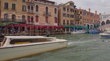 Venedik 'teki Büyük Kanal' daki Rialto Köprüsü 'ne nakliye turu. Gondolcular gondolda kürek çekiyor. Yakınlarda, bir su taksisi ve diğer teknelere gidin..