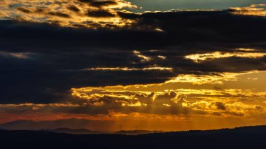 Kara Orman 'da dramatik bir gün batımı. Hafif vuruşlar ve rüzgar jeneratörlerinin siluetleri.