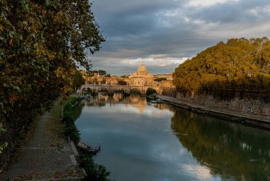 Roma 'daki Kubbe Aziz Peter Bazilikası' nı gün batımında Tiber nehrinin üzerindeki köprüden muhteşem renkler ve İtalya 'da yansımalarla görüyoruz.