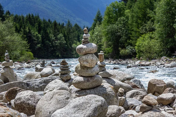 Harmony, balance and simplicity concept. A stone pyramid on the background of river water. Simple poise pebbles, rock zen. Blue, life.