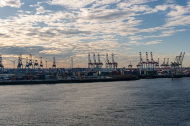 Hamburg konteynır limanında bazı gemiler gün batımında yük gemilerine konteynır yüklüyor ve naklediliyor.
