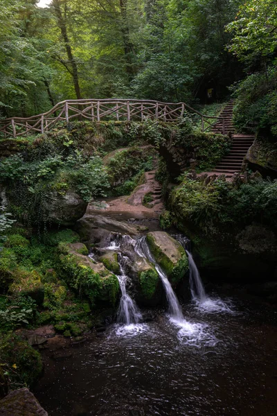 Lüksemburg 'da çağlayan şelaleler üzerinde köprü ile çekilen mistik orman - Mullerthal, Lüksemburg' da Schiessentuempel olarak bilinen üç küçük şelale (Küçük İsviçre olarak da bilinir))