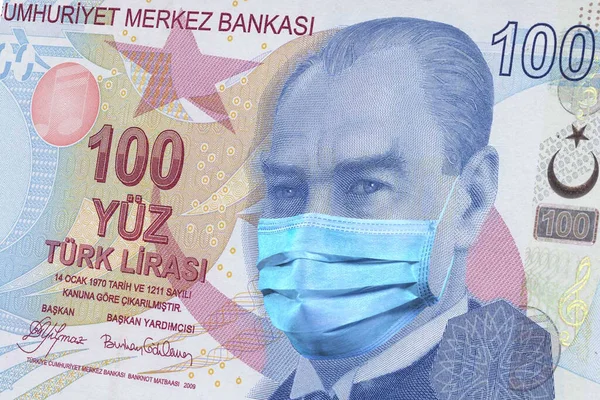 100 Lira Turkish banknote with a medical mask. coronavirus epidemic in Turkey the impact of the coronavirus epidemic on the economy and currency of Turkey