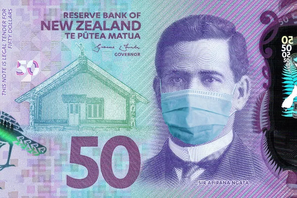 Yeni Zelanda 'da 50 dolarlık banknotlar ve tıbbi bir maske. Yeni Zelanda 'daki koronavirüs salgınından. Koronavirüs salgınının Yeni Zelanda ekonomisi üzerindeki etkisi. Yeni Zelanda para biriminin devalüasyonu