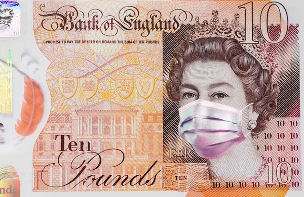 10 banknote in the UK with Queen Elizabeth in a medical mask. the impact of the coronavirus epidemic on the UK economy . impact of the coronavirus epidemic on the British pound