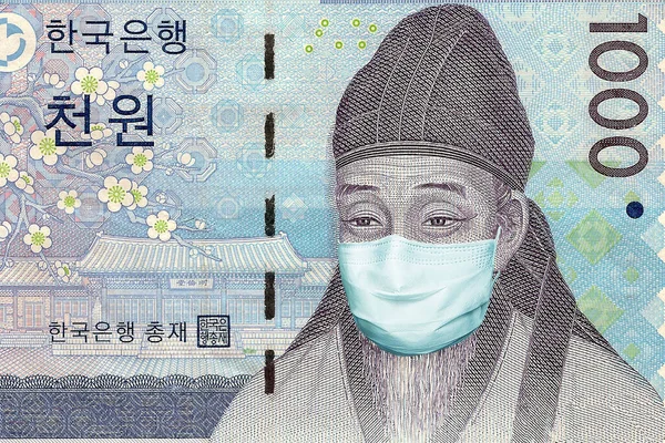 1000 Korean won banknote with a medical mask. Coronavirus epidemic in South Korea. The fall of the South Korean economy due to the coronavirus epidemic