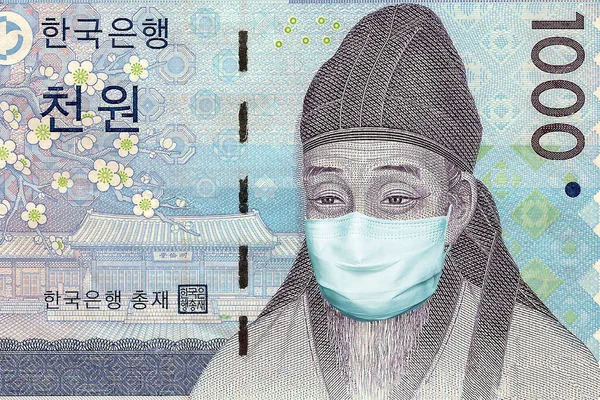 Tıbbi bir maskeyle 1000 won 'luk banknot. Güney Kore 'de koronavirüs salgını. Koronavirüs salgını yüzünden Güney Kore ekonomisinin çöküşü.