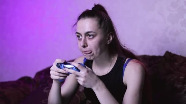 心满意足的女孩在玩电子游戏 手里拿着一个游戏垫 在椅子上吃着薯片 家中被隔离的妇女的红色蓬乱的头发 — 图库视频影像