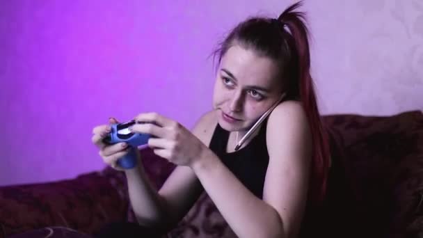 女の子は電話で話すことによってビデオゲームから気が散る 電話に答える時間がない ゲーマーはビデオゲームに熱心です 携帯電話での会話を — ストック動画