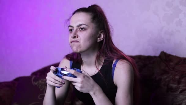 게임을 소녀는 게임에 집중하고 적에게 악의적으로 미소를 짓는다 소파에서 감정을 — 비디오