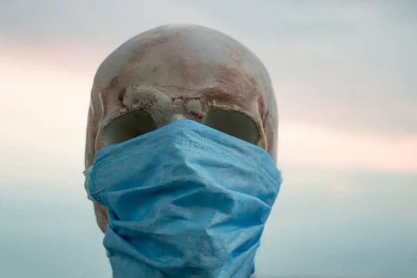 masked human skull on a background of clouds. medical protection against coronavirus.