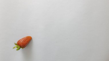 Mavi kart arkaplanı ve sol altta yeşil yapraklı küçük kırmızı çilek.