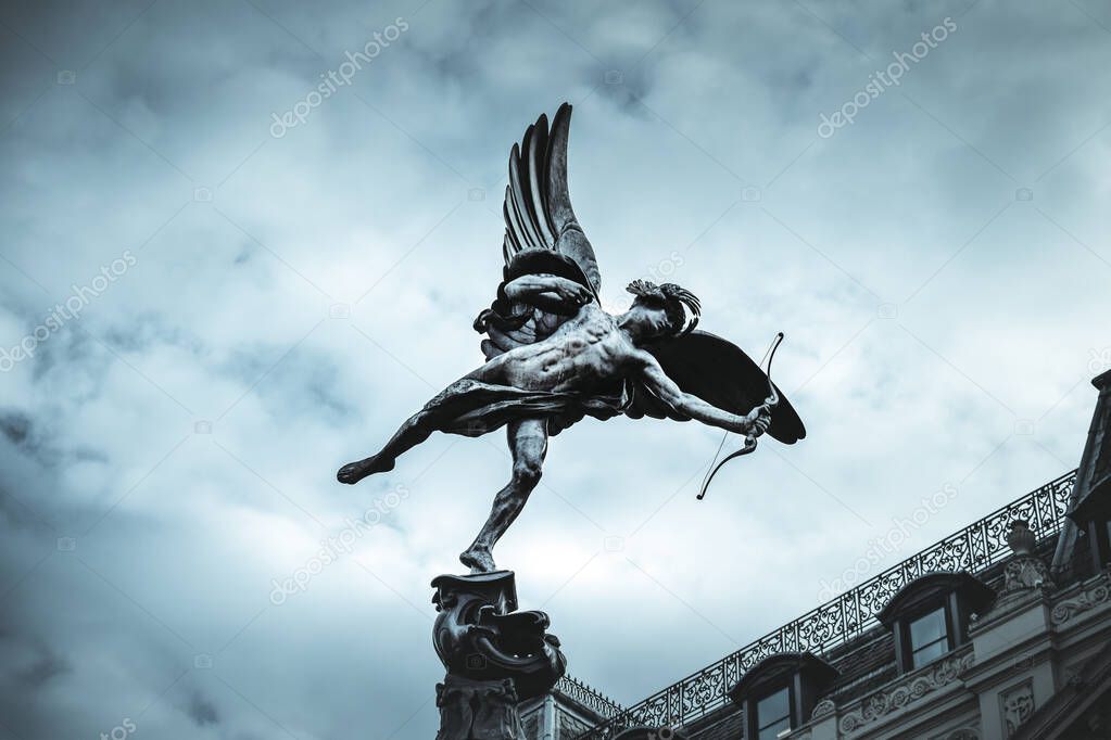 Famous statue of Eros, Amor, Cupid at Piccadilly Circus in London, UK, on blue clear sky and dramatic background