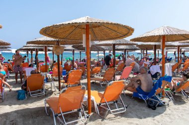 Paralia, Yunanistan - 09.15.2019: güneşli yataklar ve plajda dinlenen insanlar