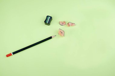 Siyah kalem açacağı ve kalem talaşı yanında duran kırmızı uçlu koyu siyah bir kalem.