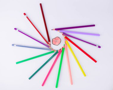 İzole edilmiş beyaz bir arka planda tıraş olurken kalem etrafında dolanan bir avuç balmumu boya kalemi ve tahta kalemler.