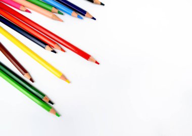 Farklı renklerde mum boya kalemleri parlak beyaz bir arka plana rastgele dağılmış.