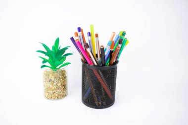 Bir ağaç ve farklı renkte kalemlerle dolu bir kavanoz beyaz bir arkaplan önüne konmuş.