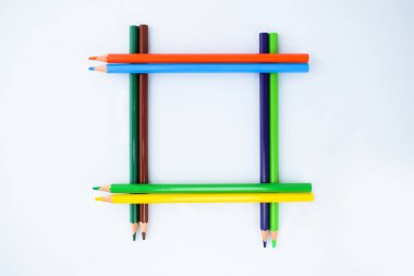 Beyaz arka planda izole edilmiş sekiz farklı renkli kalem boyasından oluşan bir çerçeve.