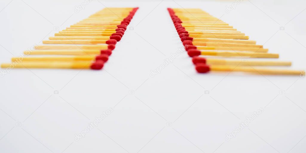 Wooden red match sticks arranged in two similar row while facing each other on a white background