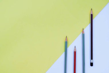 Farklı renklerde dört tahta kalem boyası renkli bir arka planda izole edilmiş.