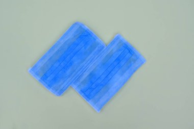 Açık mavi cerrahi maske ve açık mavi arka planda izole edilmiş beyaz lastik kayışlar.