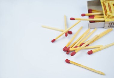 Beyaz bir arkaplan önünde küçük bir kibrit kutusunun yanına saçılmış yanıcı kırmızı yangın kibritlerinin resmini kapat