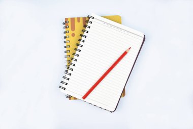 Kağıt arkaplanda kırmızı tahta kalemli bir kalemin olduğu iki günlük.