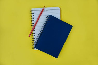 Sarı kağıt arkaplanda, üzerinde kırmızı kalem boyası olan iki günlük.