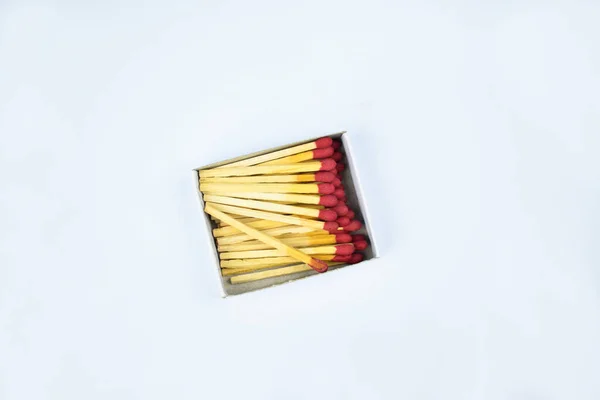 Some flammable red fire matches gathered in a small match box before a white paper background