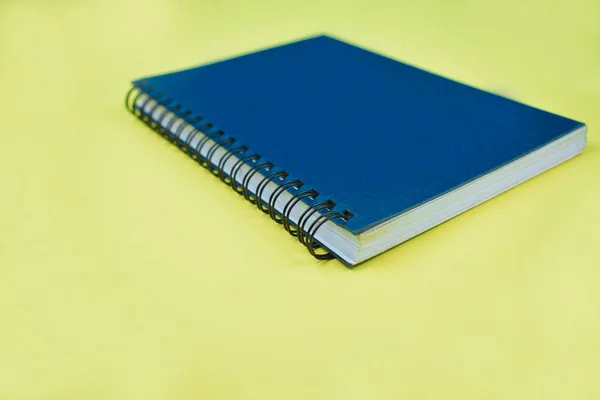 黄色の紙の背景の前に完全に青の普通の日記の側面図 — ストック写真