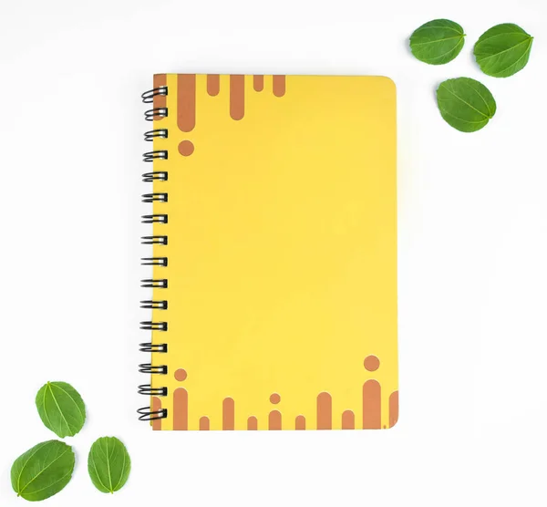 1枚の黄色の日記で 6枚の緑の葉を紙の背景の前の境界としている — ストック写真