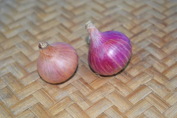 İki orta boy kırmızı soğan ahşap bir halının üzerine yerleştirilmiş.
