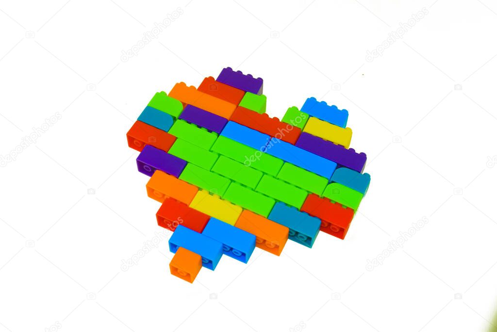 Heart shape made with lot of different colored building blocks in front of an isolated white background