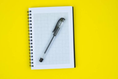 Siyah renkli tükenmez kalem, sarı kağıttan bir arka planda beyaz bir günlüğün üzerine konur.