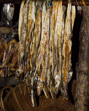 Kuru bir balığın çitlerinden sarkan bir avuç taze kuru balık.