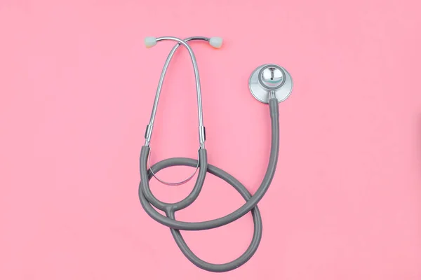 Tek bir normal steteskopun normal görüntüsü pembe renkli boş bir kağıdın üzerinde izole edilmiş.