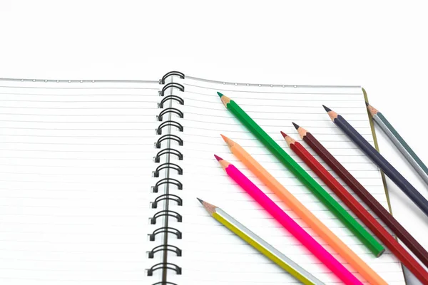 白い紙の日記の前に波状に並べられた様々な色の鉛筆のクレヨン — ストック写真