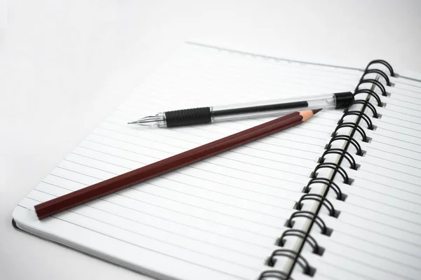 茶色の鉛筆と開いた白い日記の上に置かれた黒い色のペン — ストック写真