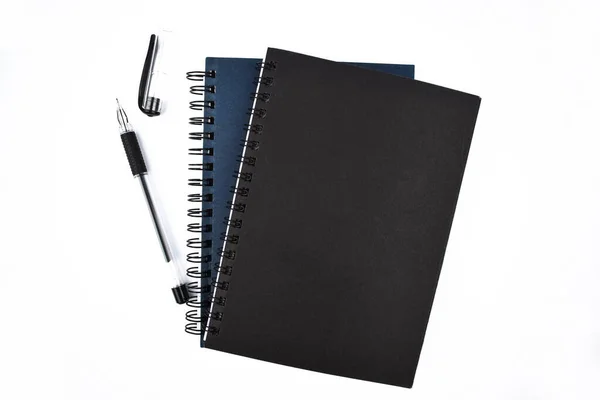 一堆蓝色和黑色的笔记本日记本和一支黑色圆珠笔放在一个白色的背景上 — 图库照片
